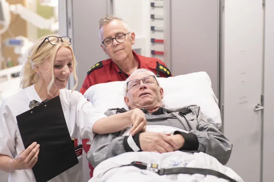 En gruppe mennesker som står rundt en person i en sykehusseng