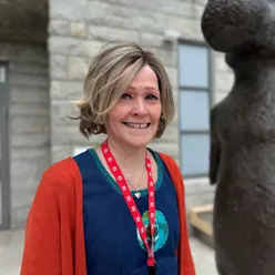 En person som smiler ved siden av en statue