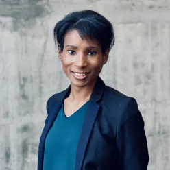 En person som smiler foran en hvit vegg