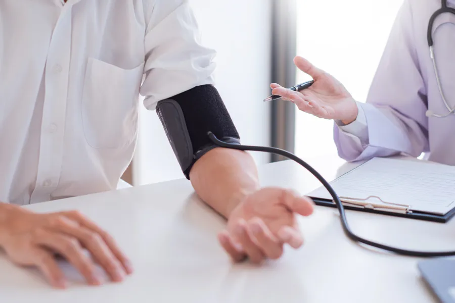 Lege som måler blodtrykk på pasient