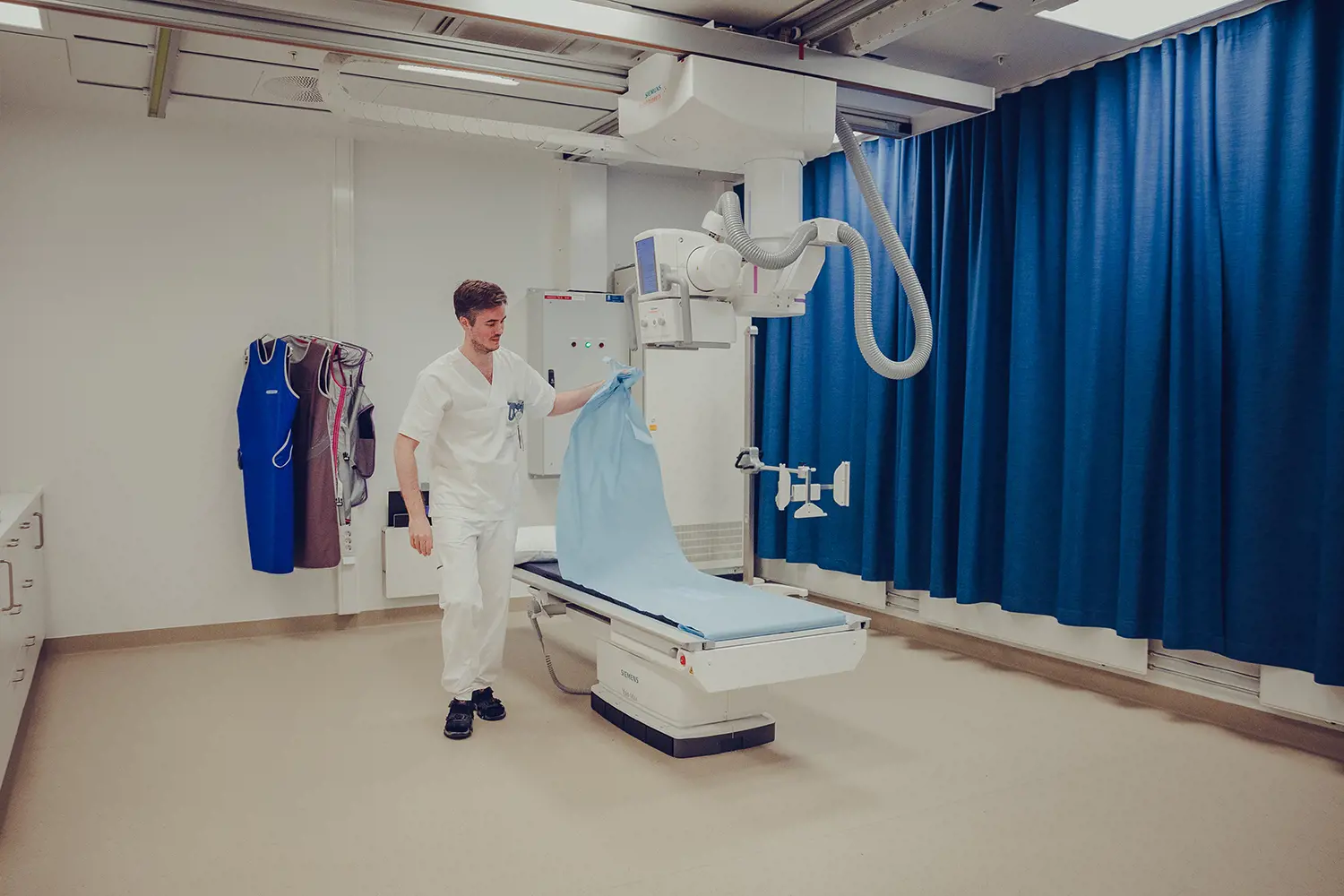 Radiolog som står ved røntgenmaskin