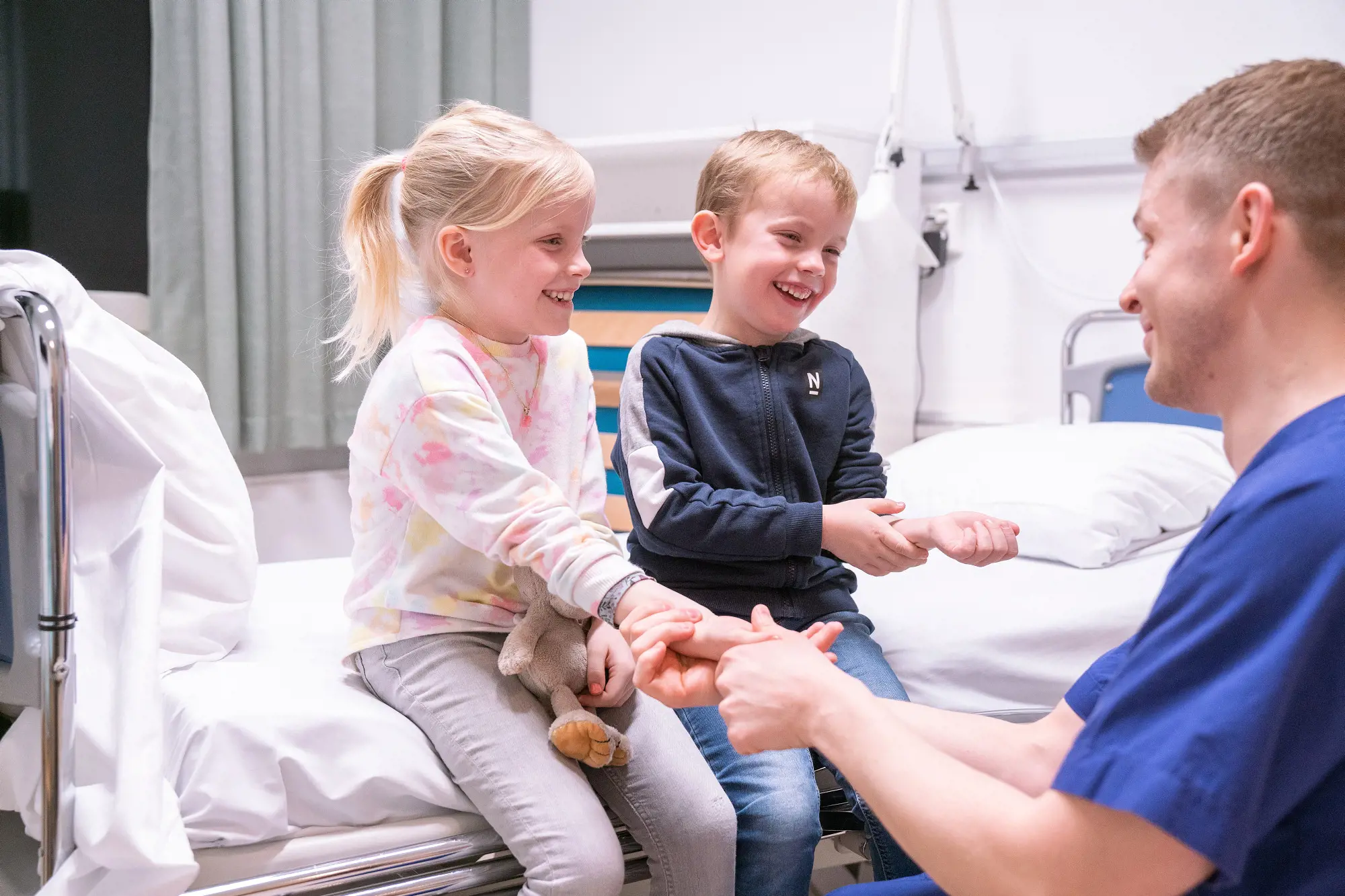 To barn som smiler og en sykepleier