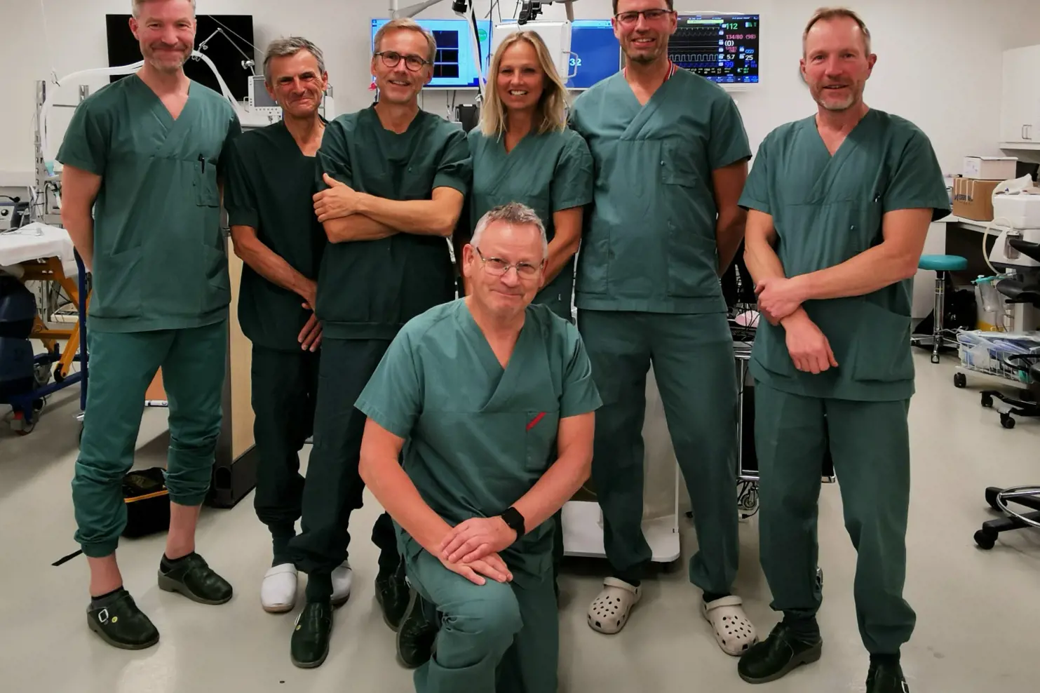 sju personer fra operasjonsstue som står samlet og smiler