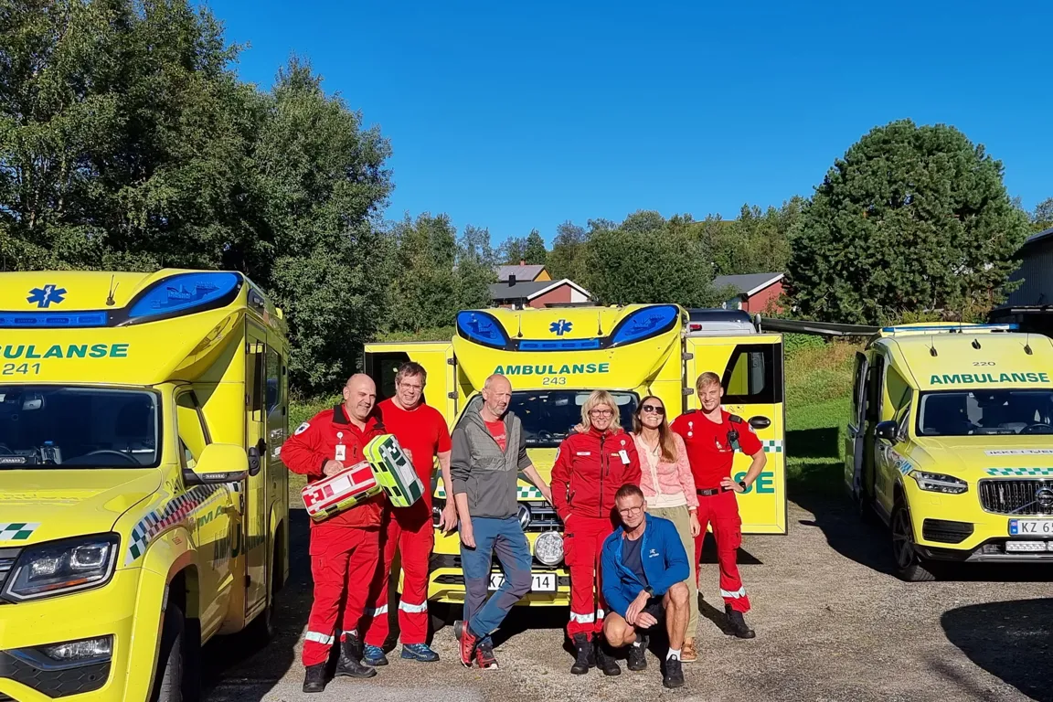 Gjeng med ambulansearbeidere smilende mot kamera