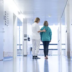 Dame som går i sykehuskorridor med en ungdom