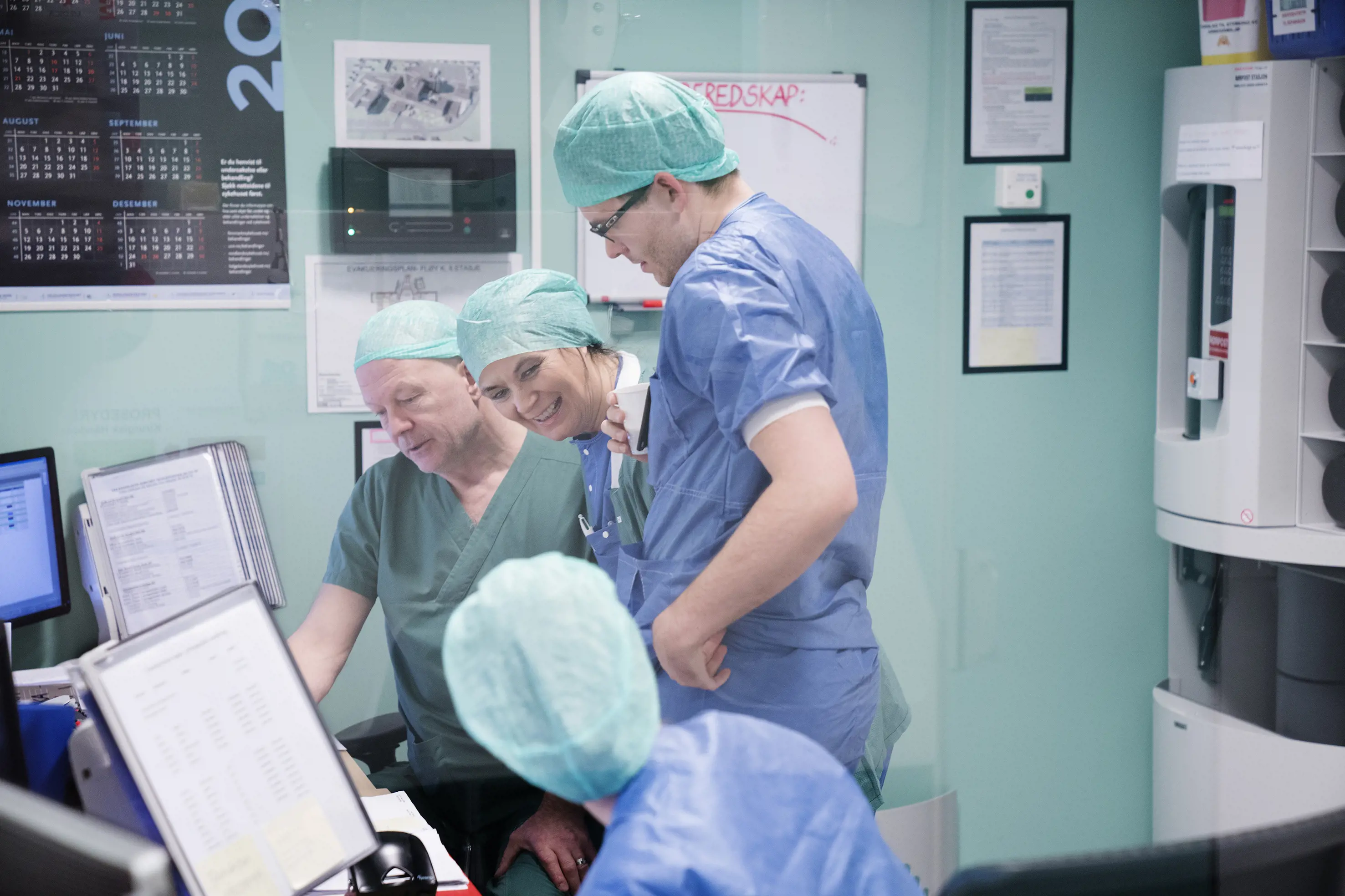 Fire pesoner i operasjonsklær som prater sammen