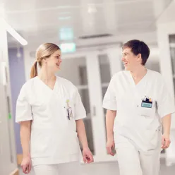To sykepleiere som prater og går i en gang