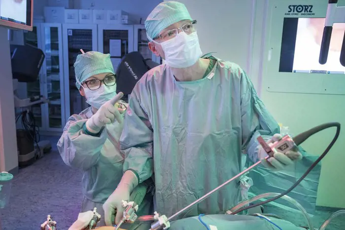 To personer som har på seg fullt operasjonsklær i en operasjonssal