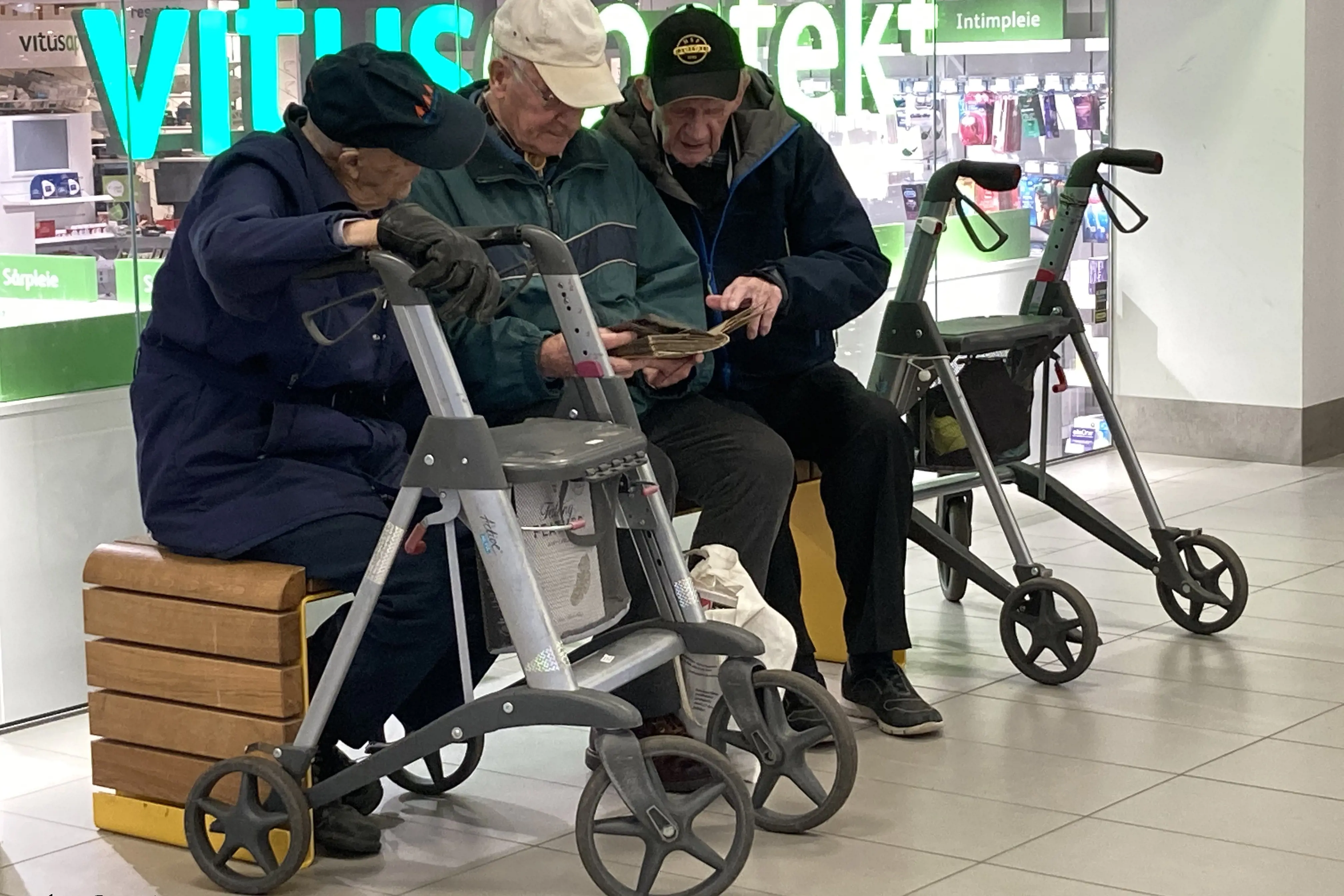 Tre gamle menn på en benk på et kjøpesenter