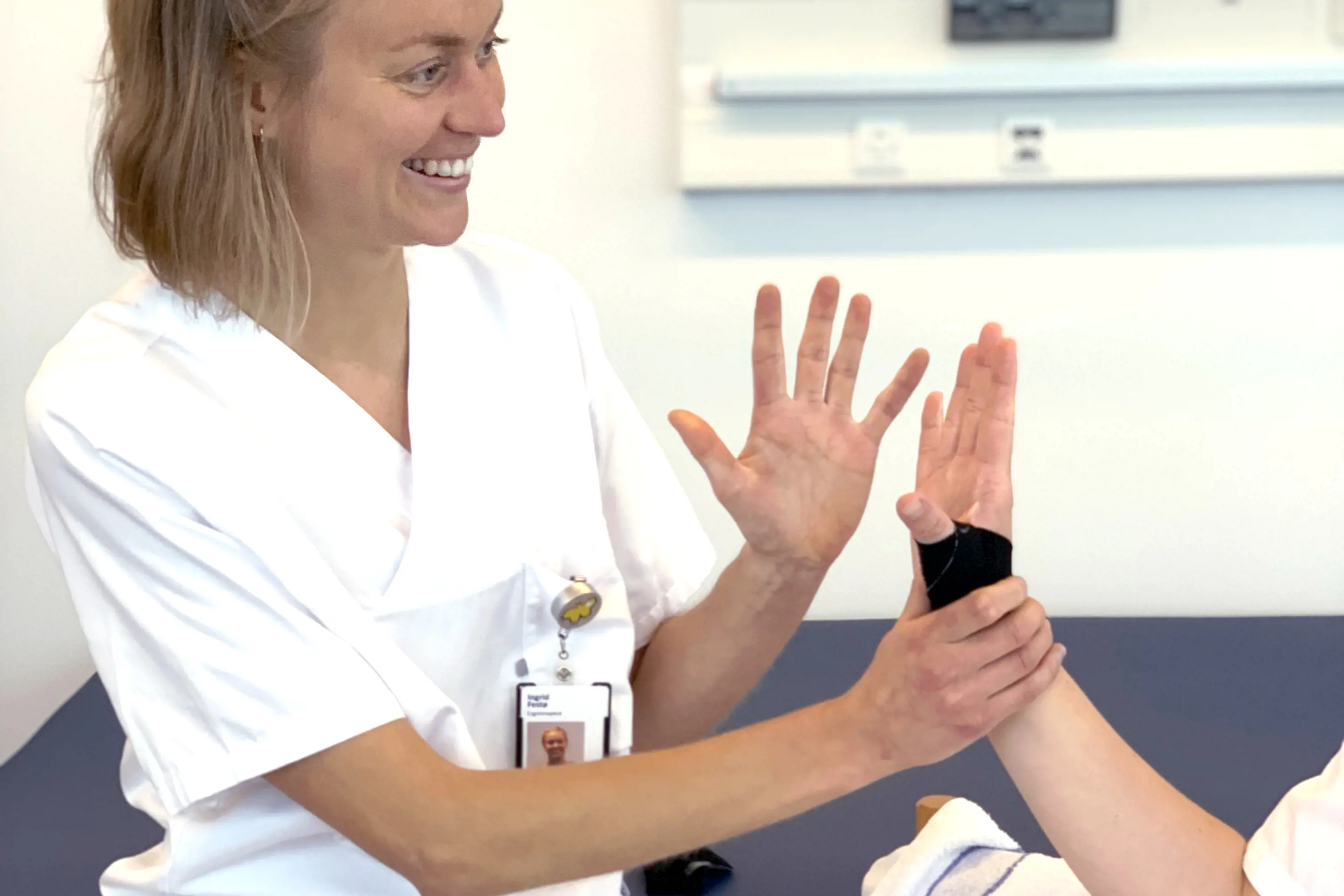 Smilende ergoterapeut som trener hånden