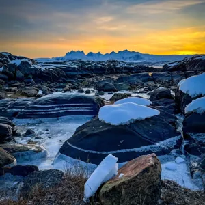 En steinete strand med snø
