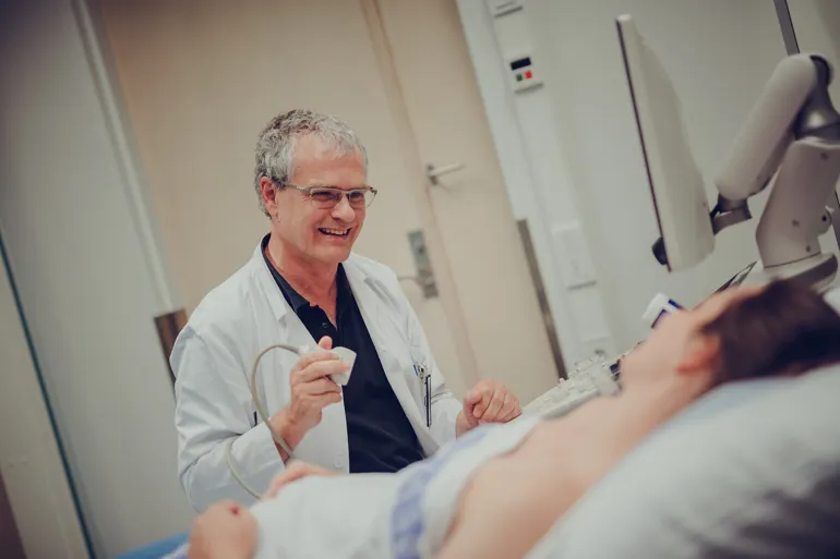 Mann som smiler og prater til pasient